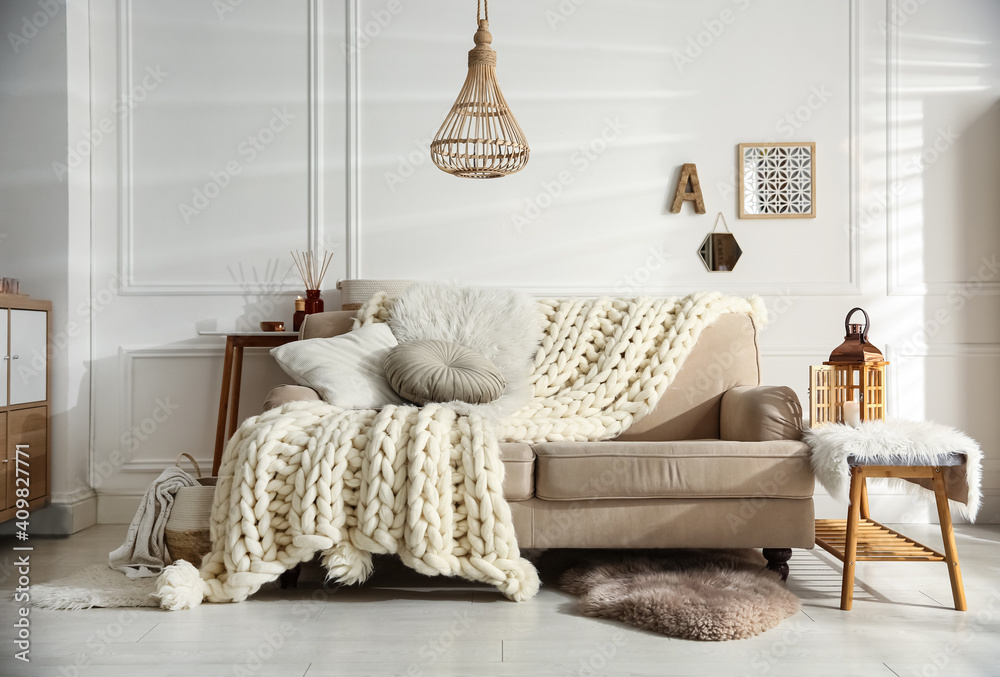 Wall mural cozy living room interior with beige sofa, knitted blanket and cushions