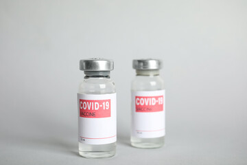 Vials with coronavirus vaccine on light background