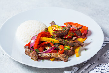 Peruvian cuisine concept. Lomo saltado - fried beef with peppers, onion, potato and rice on white...