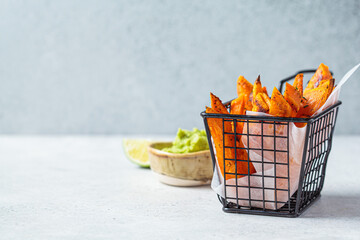 Sweet potato fries in metal basket with guacamole, gray background. Vegan food concept.