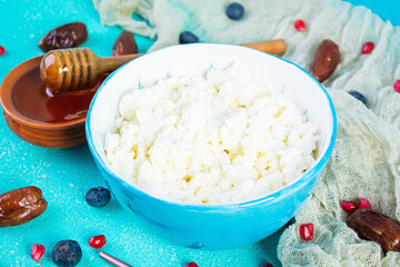Cottage cheese with honey and berries on blue background. Light vegetarian breakfast