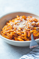 Gnocchetti sardi pasta in tomato sauce with cheese, gray background. Italian pasta concept