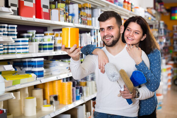 Female and male are deciding on best paint in paint supplies store.