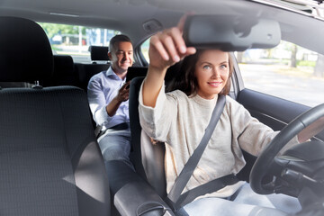 transportation, vehicle and people concept - happy smiling female driver driving car with male...