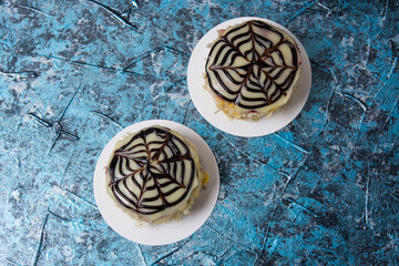 Two delicious cakes with almond chips with chocolate, frosting and cream on blue background with copy space top view