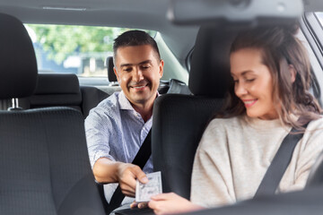 transportation, vehicle and payment concept - female car driver taking money from male passenger