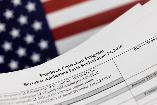 selective focus photo of paycheck protection program borrower application form revised, on a background of United States flag. paycheck protection program new round.