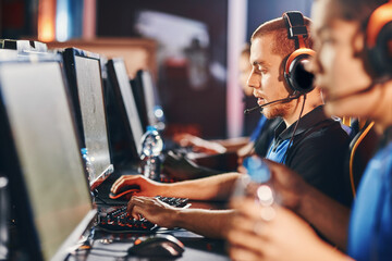 Side view of a focused ,professional male gamer wearing headphones playing online video games, participating in eSport tournament