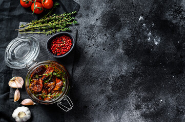 Recipe for cooking dried tomatoes in olive oil with spices and herbs. Black background. Top view. Copy space