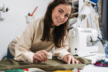 Portrait of happy seamstress sewing in the workshop - obrazy, fototapety, plakaty