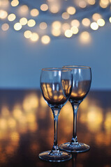 Empty glasses of wine on glass table with bokeh background close up. New Year, Christmas mood. Greeting card. Party and holiday celebration concept.