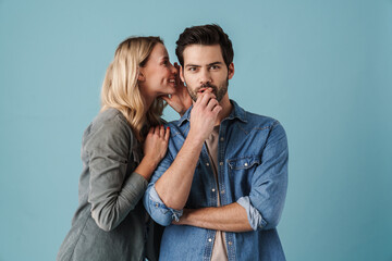 Young beautiful woman whispering secret at surprised guy