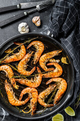 Fototapeta na wymiar Grilled giant prawns, shrimps with garlic, lemon, spices in pan. Black background. Top view