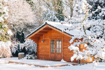 Wooden garden shed covered with snow. First snow. Winter in the garden