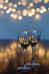 Empty glasses of wine on glass table with bokeh background close up. New Year, Christmas mood. Greeting card. Party and holiday celebration concept.