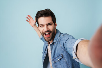 Young excited man showing copyspace while taking selfie photo