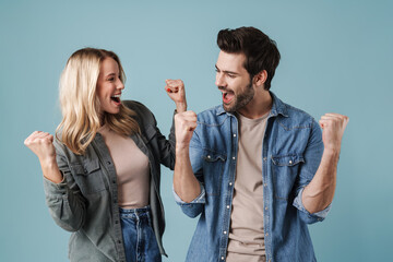 Young excited man and woman screaming and making winner gesture