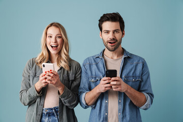 Young delighted man and woman exclaiming while using mobile phones