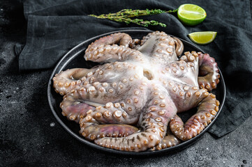 Fresh octopus with cooking ingredients, lime, thyme, chili pepper. Black background. Top view.