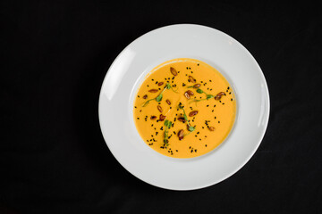 Yellow vegetable pureed soup in a white plate