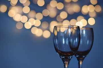 Empty glasses of wine on glass table with bokeh background close up. New Year, Christmas mood. Greeting card. Party and holiday celebration concept.