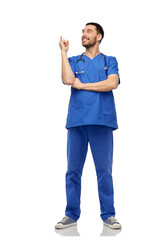 healthcare, profession and medicine concept - doctor or male nurse in blue uniform with stethoscope pointing finger up over white background