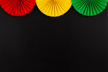 Red, yellow and green color origami flowers on the black background.