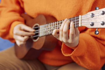 Girl learns to play the ukulele at home