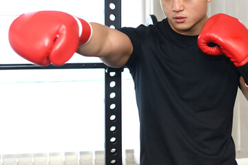 ボクシンググローブをつけてパンチを打つ若い男性 - obrazy, fototapety, plakaty