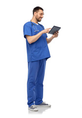 medicine, healthcare and technology concept - happy smiling doctor or male nurse in blue uniform with stethoscope using tablet pc computer over white background