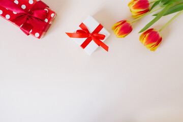 A bouquet of red spring flowers tulips and red gift boxes on white table with copy space. Valentine Day