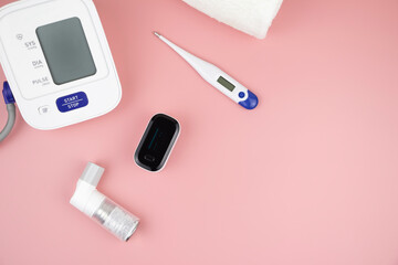 inhaler, pulse oximeter and other measuring medical devices on a pink background