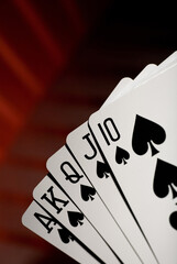 Close up of a royal straight flush in spades on red background. Studio photo.