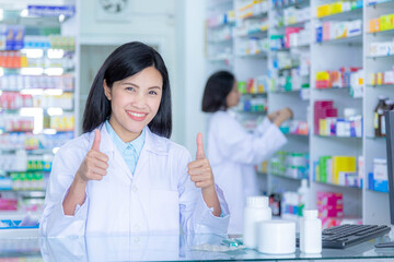 Asian pharmacists thumbs up with happy work at pharmacy drugstore.
