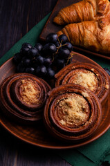 cinnamon bun with grape and croissant on  green cloth