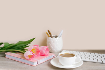Pink tulips with a festive spring mood and coffee on a wooden table Women's work, home office and career concept. Side view. Copy space