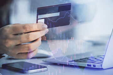 Multi exposure of woman on-line shopping holding a credit card and financial graph drawing. Stock market E-commerce concept.