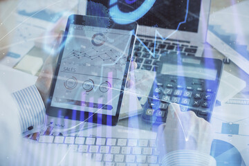 Double exposure of man's hands holding and using a digital device and forex graph drawing. Financial market concept.