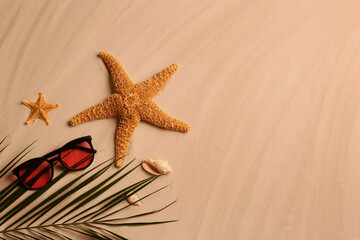 Fototapeta na wymiar Flat lay composition with stylish sunglasses and starfishes on sand, space for text. Beach accessory