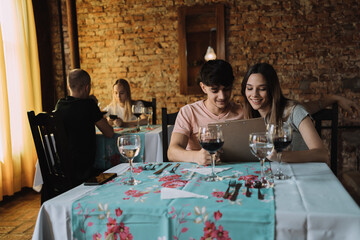 Beautiful young couple reading menu at restaurant - Young couple in love choose their food together.