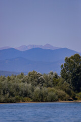 Obraz premium summer landscape with forest near a large lake and mountains on the horizon