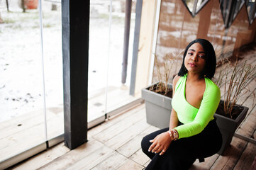 Fashionable african american woman in a light green top and black pants pose.