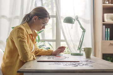 Young woman solving a puzzle at home
