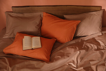 Book on bed with brown and orange linens