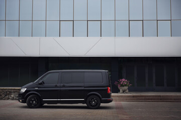 Black delivery van parked on street near building