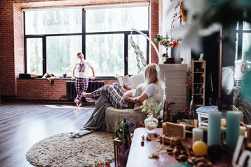 Pregnant woman reading a book in the living room lying on the couch. A young, expectant mother is reading a book on pregnancy and childbirth. Concept of pregnancy, motherhood, rest, expectation.