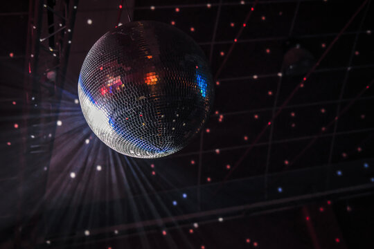 Disco ball. Mirror tiles. Bright lights. Clubbing. Party icon. Dance hall. Black background.