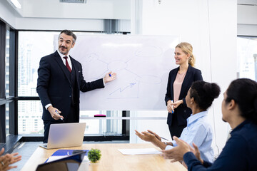 Business man and woman offering information on the board to team.