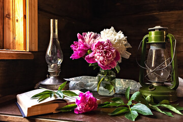 Still life of vintage items and a bouquet of peonies on a table by the window in an old village...