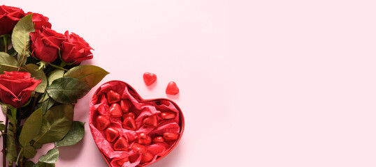 Red hearts chocolate sweets and bouquet of red roses on pink. Valentine's day banner or greeting card with copy space.